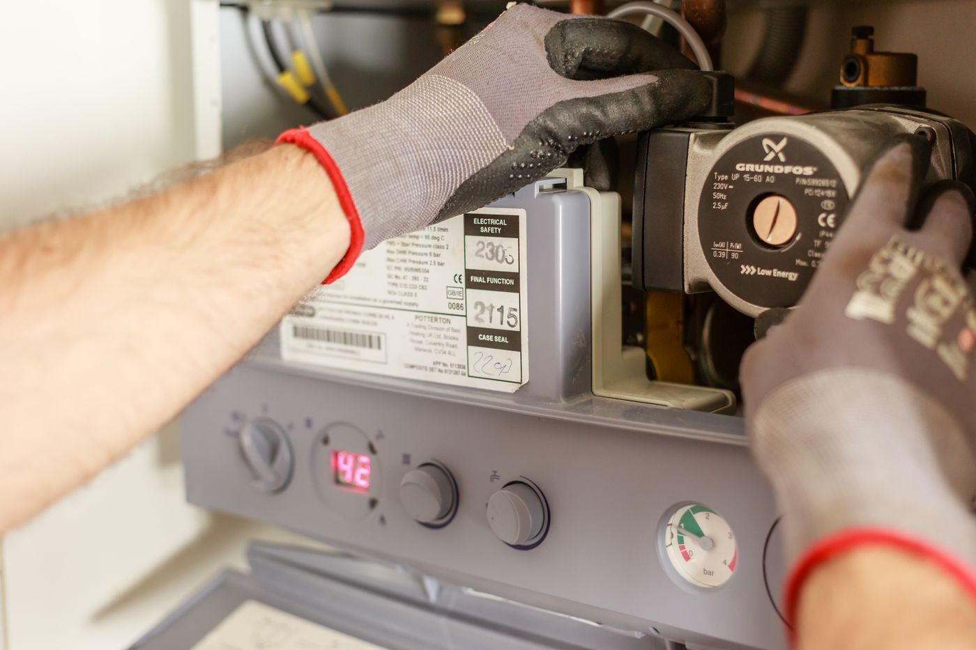 Gloved hands servicing a water heating unit