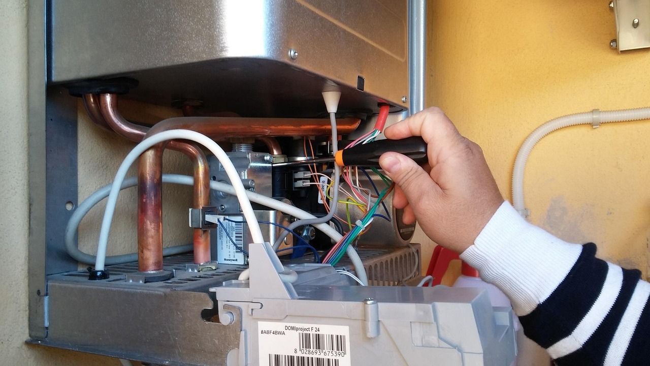 Technician servicing the wiring of a wall-mounted gas unit