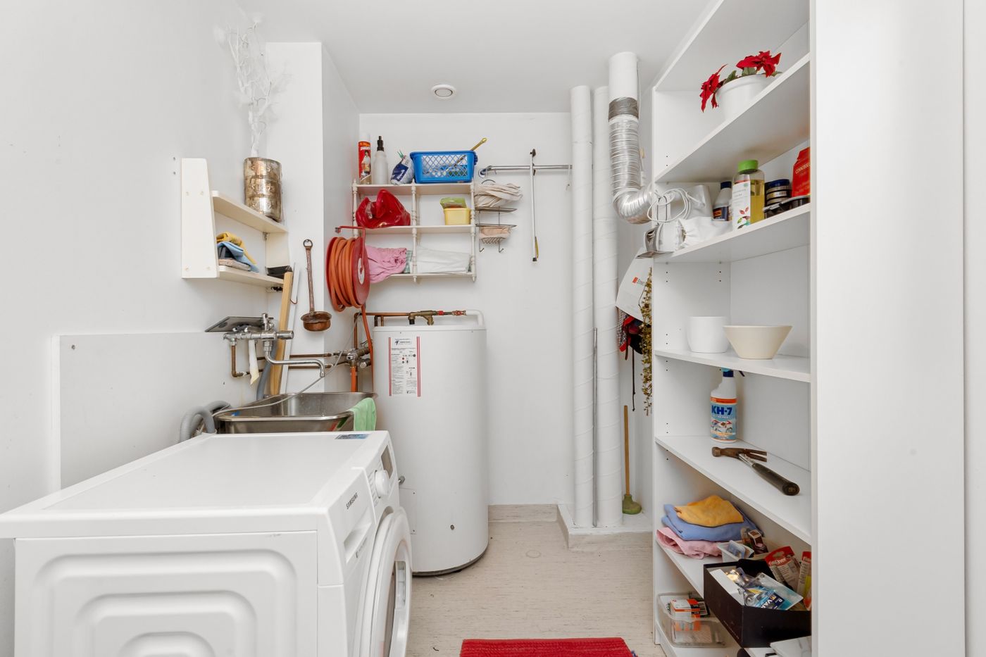 Tall water heater tank installed in a bright utility room